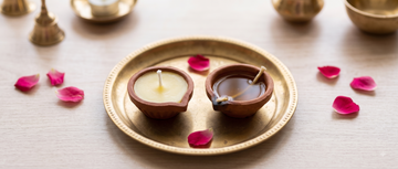 A cow ghee diya and a traditional oil diya placed side by side for comparison during puja preparation