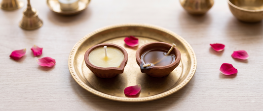 A cow ghee diya and a traditional oil diya placed side by side for comparison during puja preparation