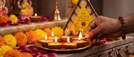 A hand lighting a pure cow ghee diya on a home altar during daily puja ritual