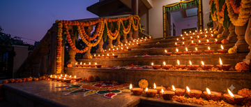 Rows of lit cow ghee diyas arranged along a decorated home entrance for Diwali