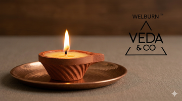 A lit pure cow ghee clay diya placed at a clean home pooja space — Veda & Co