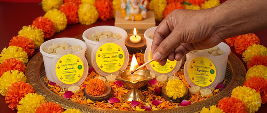 A hand lighting a ghee batti wick in a small diya during daily puja ritual