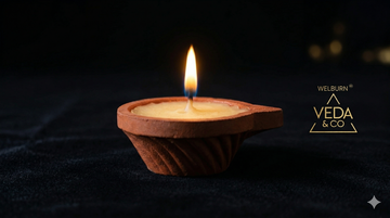 Lit pure cow ghee clay diya with a steady golden flame — Veda & Co