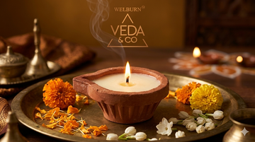 Lit ghee diya with pure cow ghee flame glowing in a traditional puja setting — Veda & Co