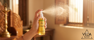 Hand spraying puja spray upright into a sunlit room