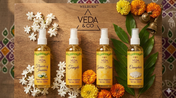 Four Veda & Co puja spray fragrance bottles — Jasmine, Camphor, Golden Flower and Temple — arranged with flowers and soft natural light, room freshener
